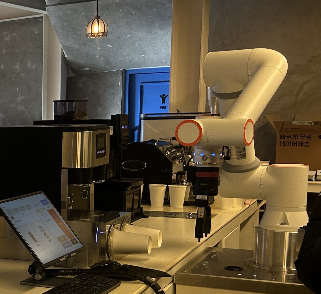 Actual commissioning process with a six-axis robot beside a coffee machine and cup dispenser